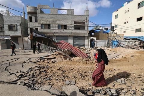 A woman walks over a destroyed road in the aftermath of an Israeli strike in Khan Yunis in the southern Gaza Strip on May 14, 2025 (AFP photo)